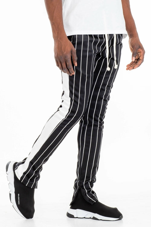 Person wearing black and white striped pants with a plain background