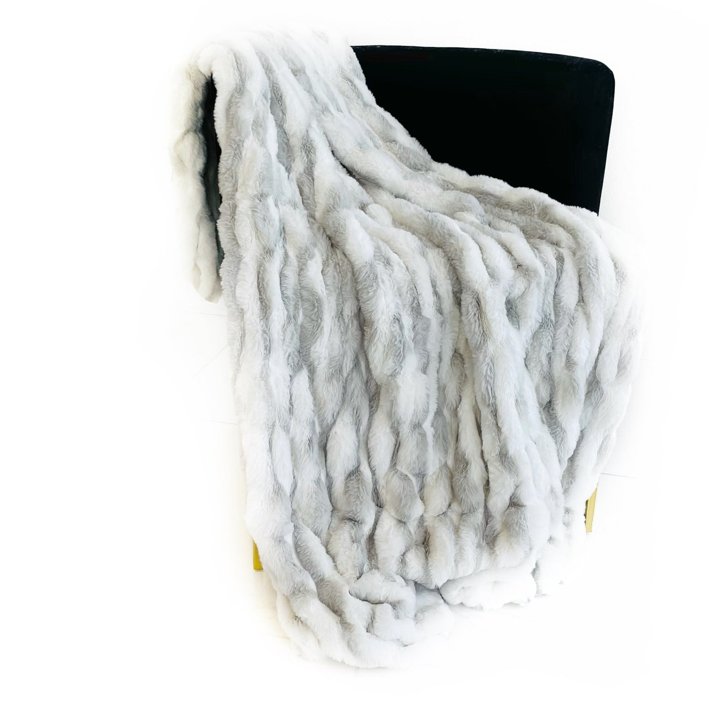 White faux fur-like throw blanket on a black chair against a white background