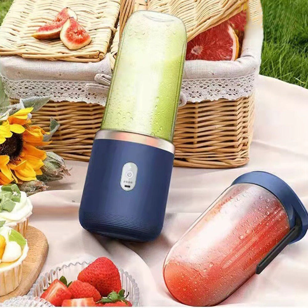 Portable blender with a green smoothie on a picnic blanket with fruits and a basket in the background.