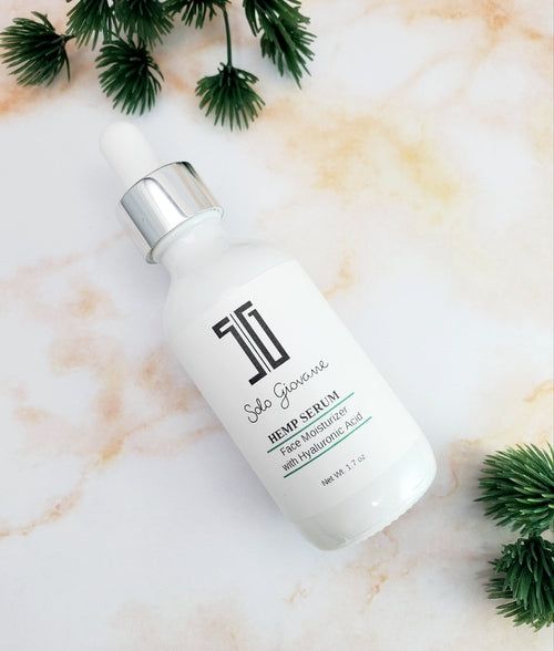 Solo Giovanne Skincare serum bottle on a marble surface with green leaves