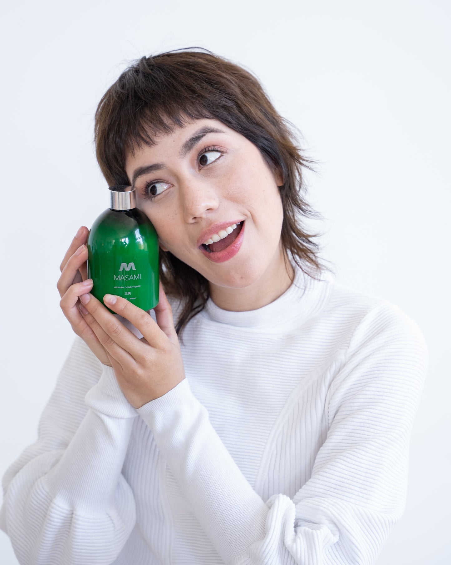 Person holding a green bottle with a white background