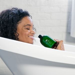 Person holding a green bottle in a bathroom setting