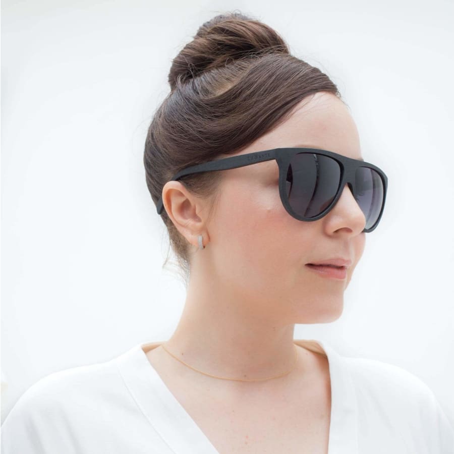 Woman wearing black sunglasses with a plain background