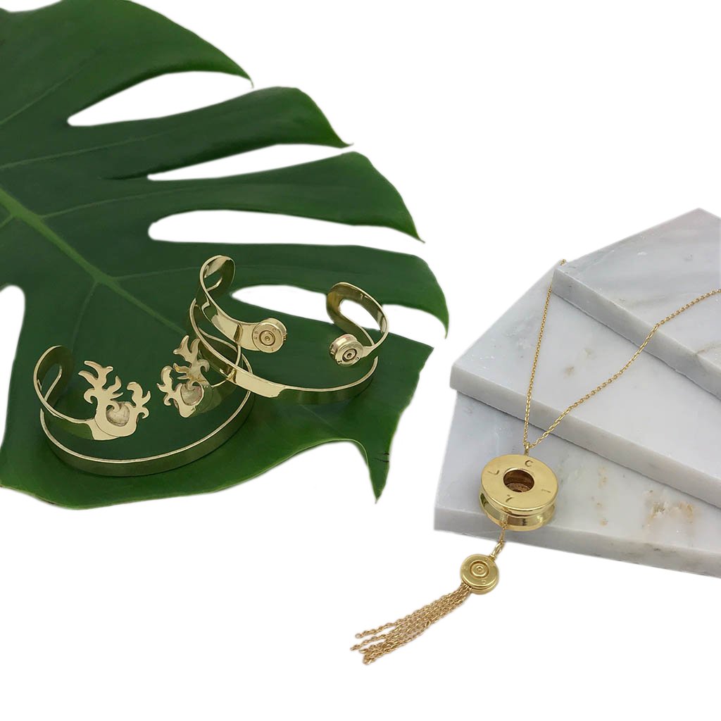 Gold bracelet and necklace on a green leaf and marble surface
