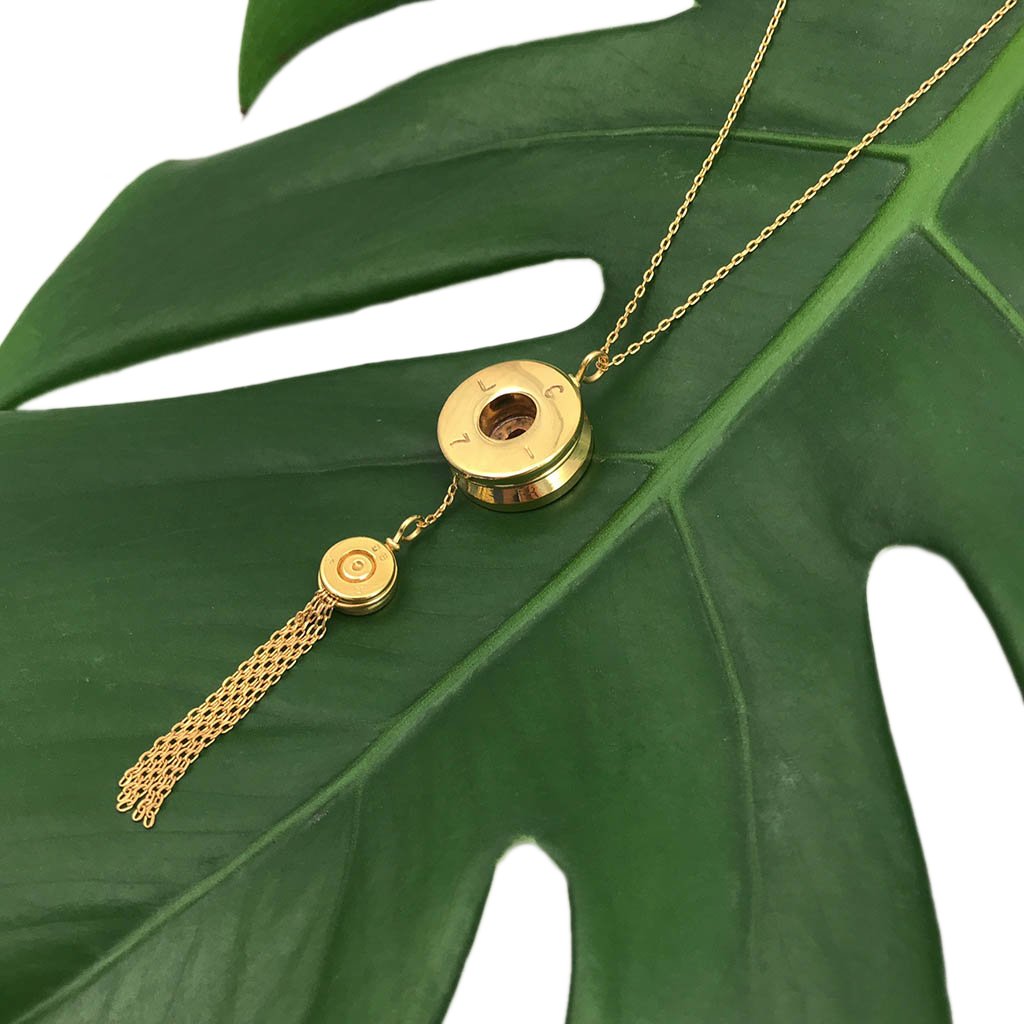Gold necklace with tassel on a green leaf