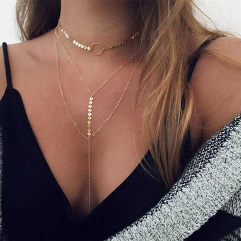 Gold body chain worn by a person with a black top and white and gray patterned fabric.