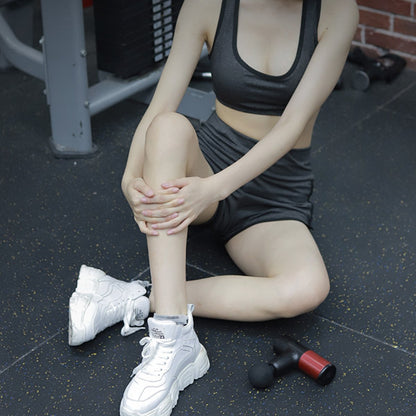 Person in athletic wear sitting on a gym floor with a dumbbell nearby
