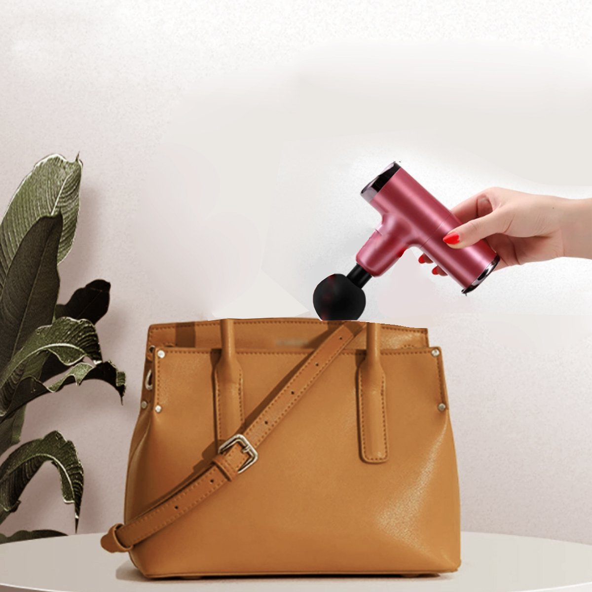 Person using a handheld device to clean a brown leather bag on a white background