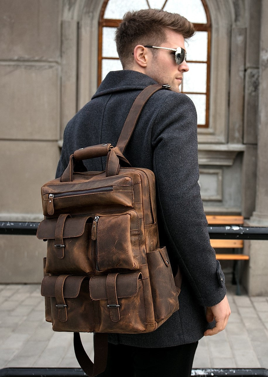 Man wearing a brown leather backpack outdoors.