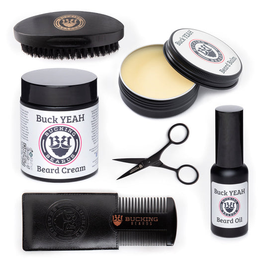 Collection of Buck Yeah beard care products including cream, oil, comb, and scissors on a white background.