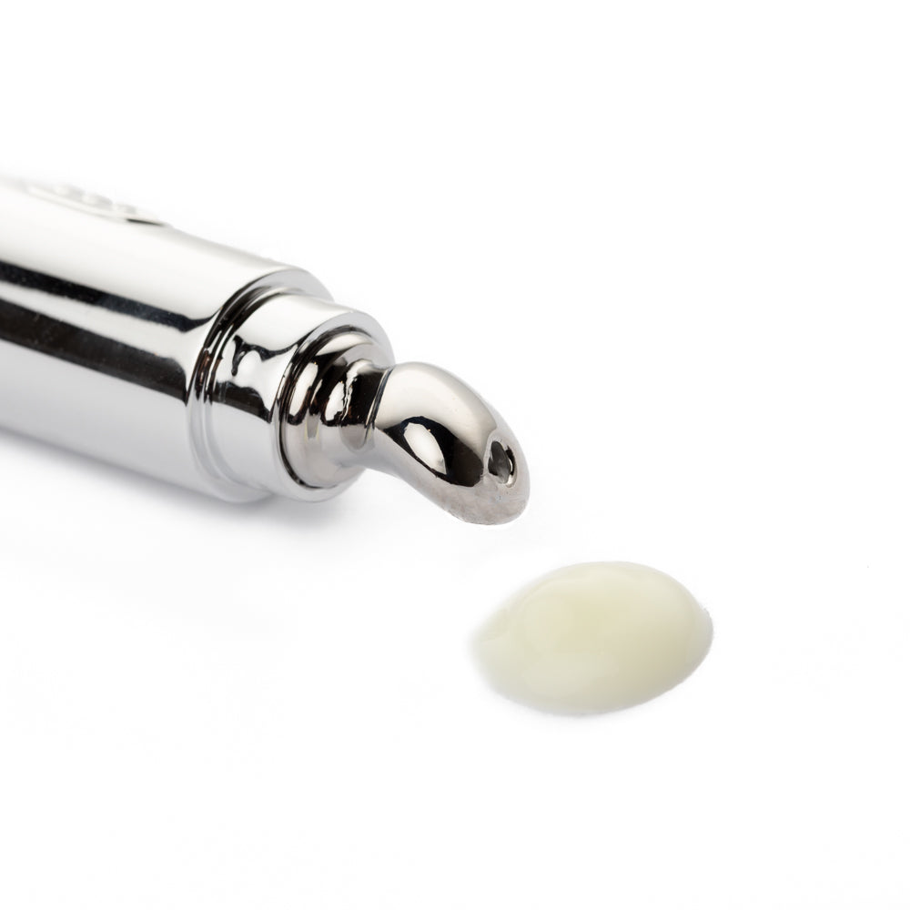 Silver cosmetic applicator with a drop of Dr. Liia anti-ageing eye cream on a white background