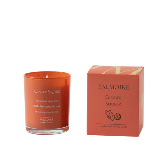 Orange candle labeled 'Ginger Squeez' by Palmoire next to its packaging on a light gray background