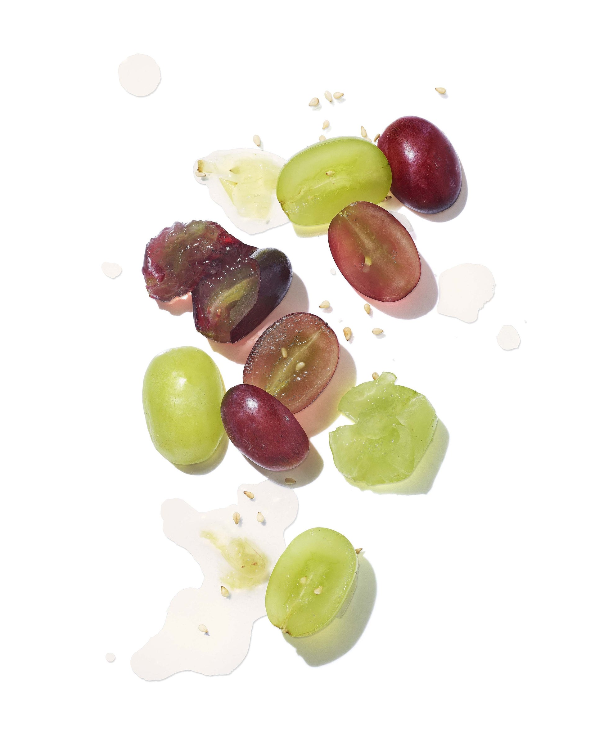 Sliced green and red grapes on a white background