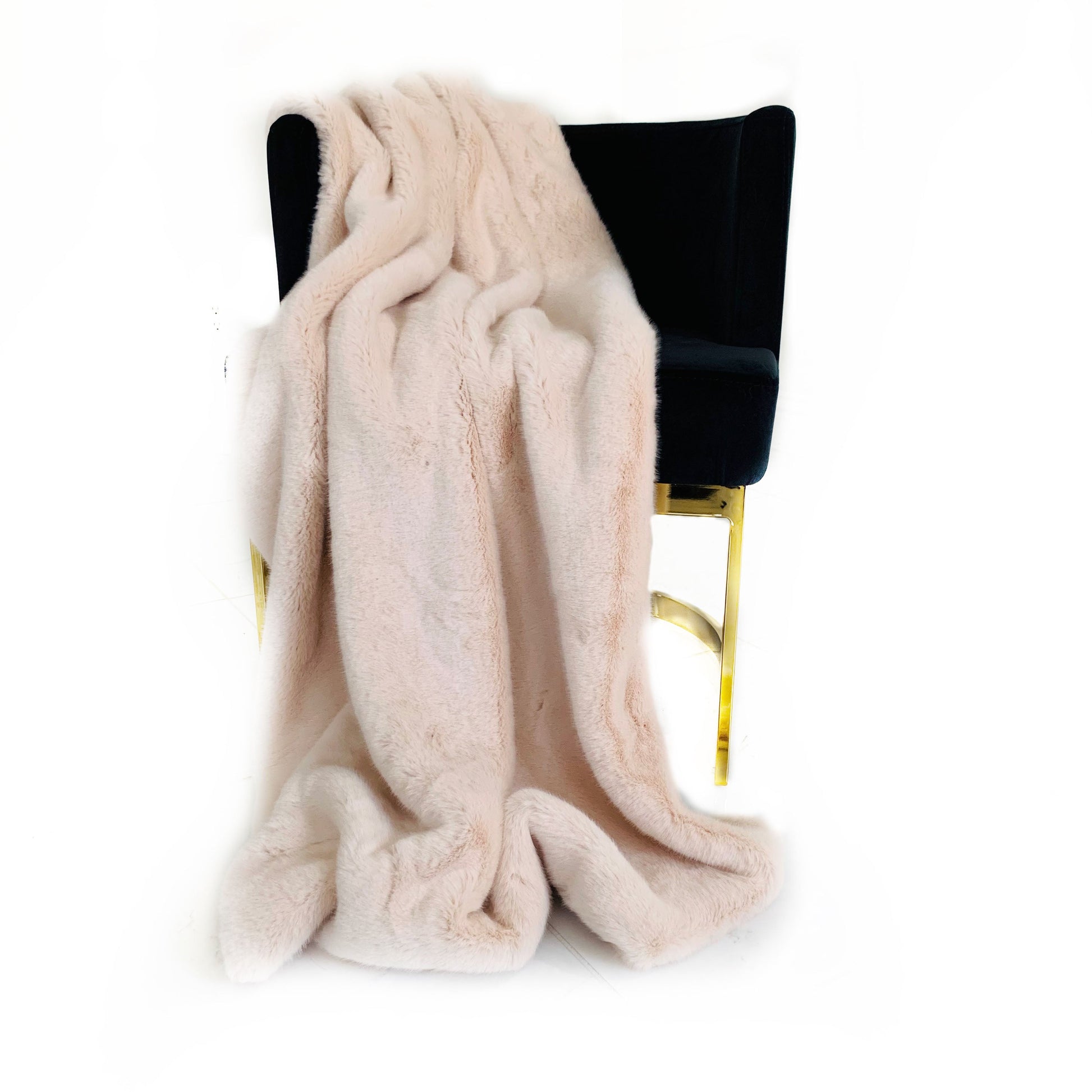 Pink colored faux fur blanket draped over a black chair on a white background