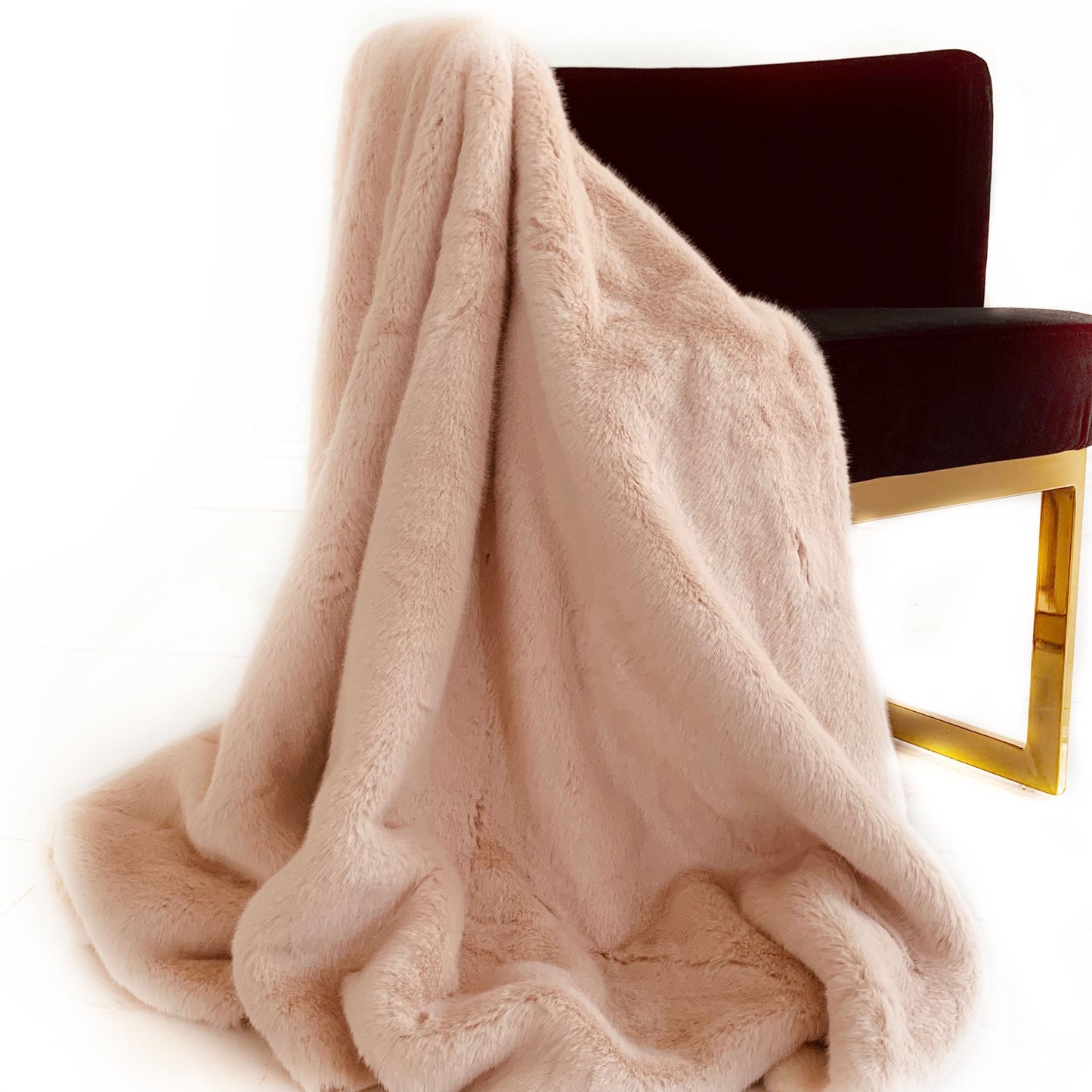 Pink plush faux fur blanket draped over a chair on a white background