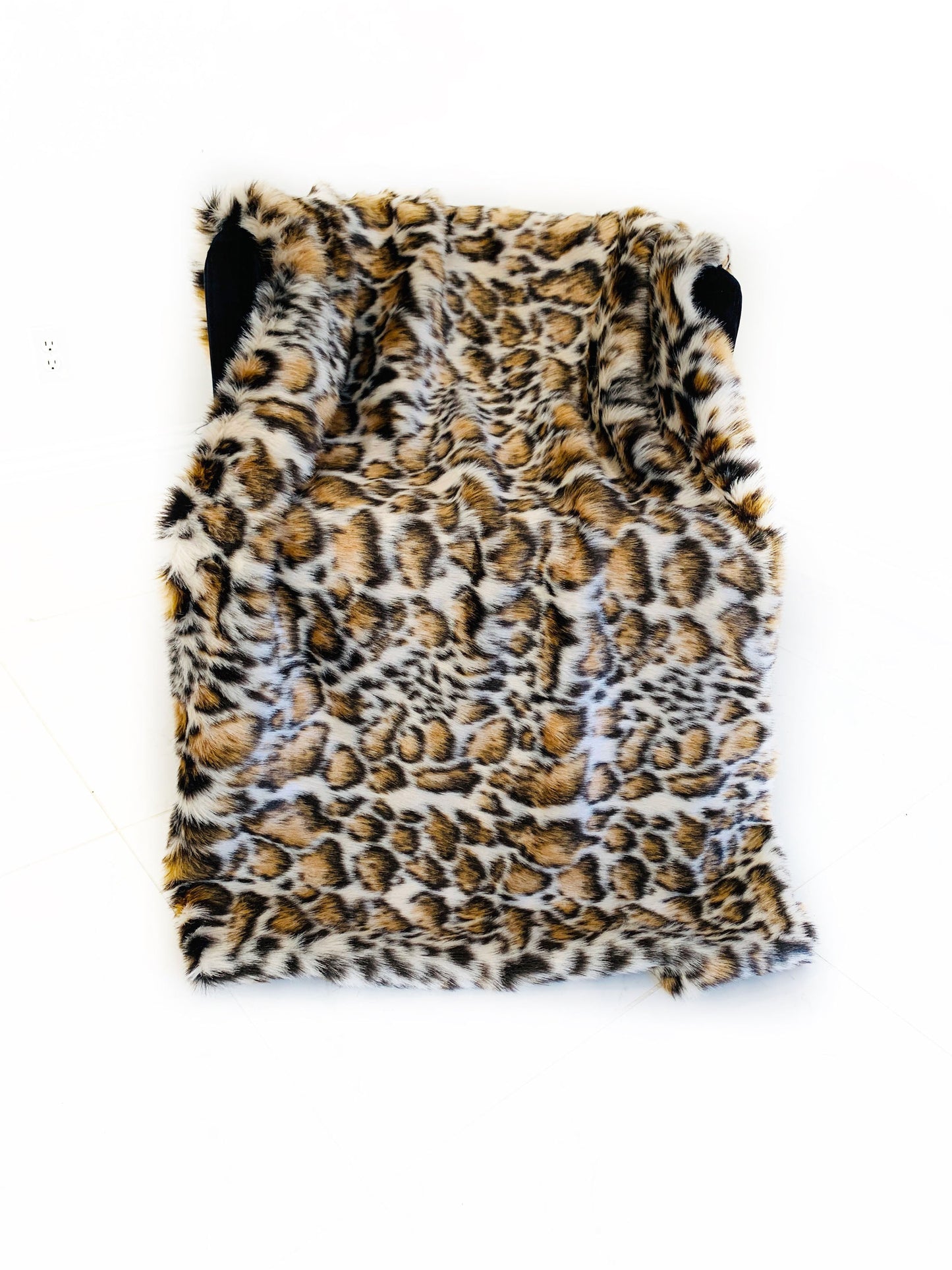Leopard print faux fur blanket on a white background