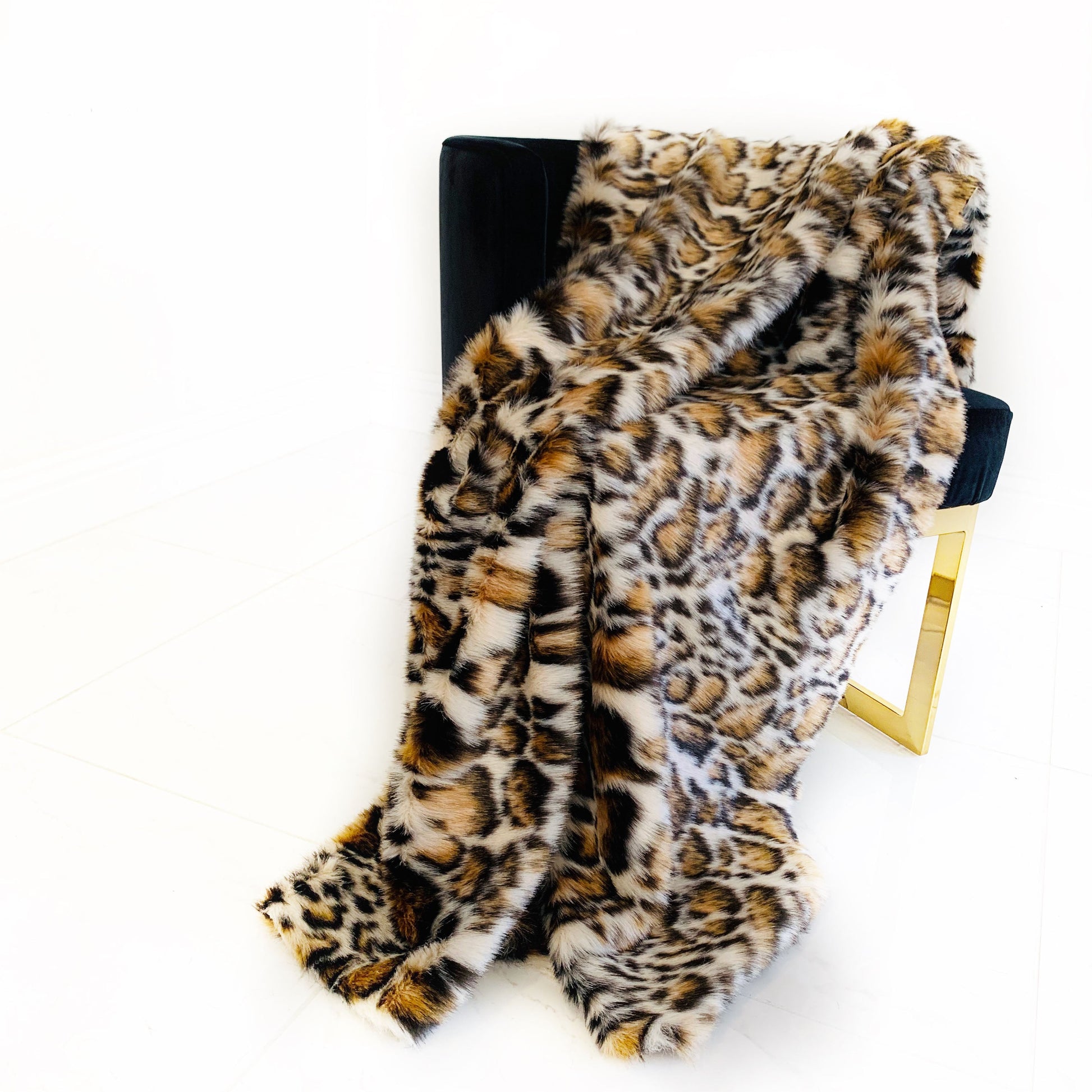Leopard print faux fur blanket draped over a chair on a white background