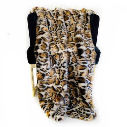Leopard print faux fur blanket draped over a black chair on a white background