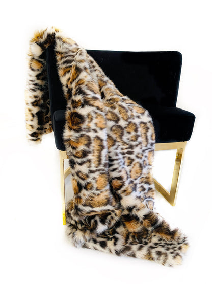 Leopard print faux fur blanket draped over a black chair on a white background