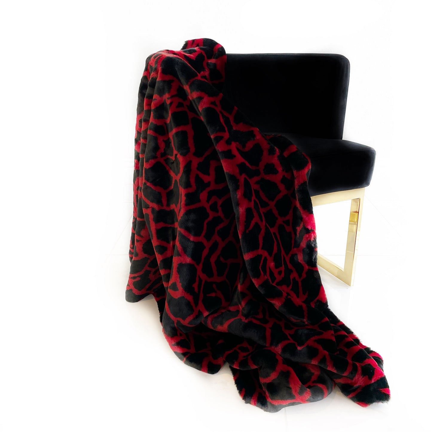 Black and red patterned blanket draped over a black chair on a white background