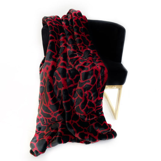 Red and black patterned blanket draped over a black chair with gold legs on a white background
