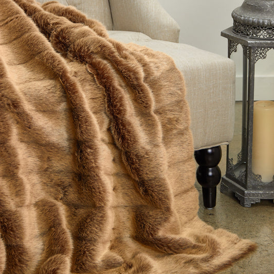 Brown fur throw blanket draped over a beige armchair with a candle and lantern in the background.