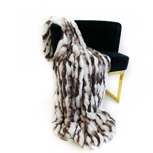 Fur throw blanket draped over a black chair on a white background