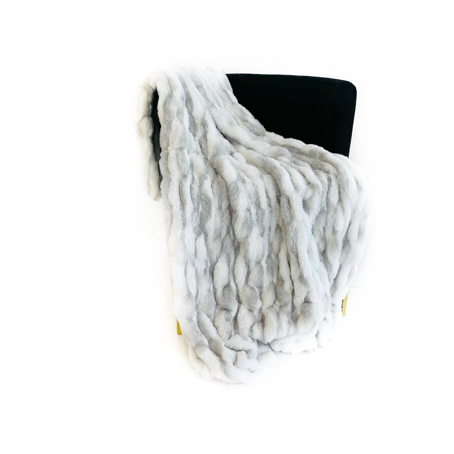 White faux fur-like throw blanket on a black chair against a white background