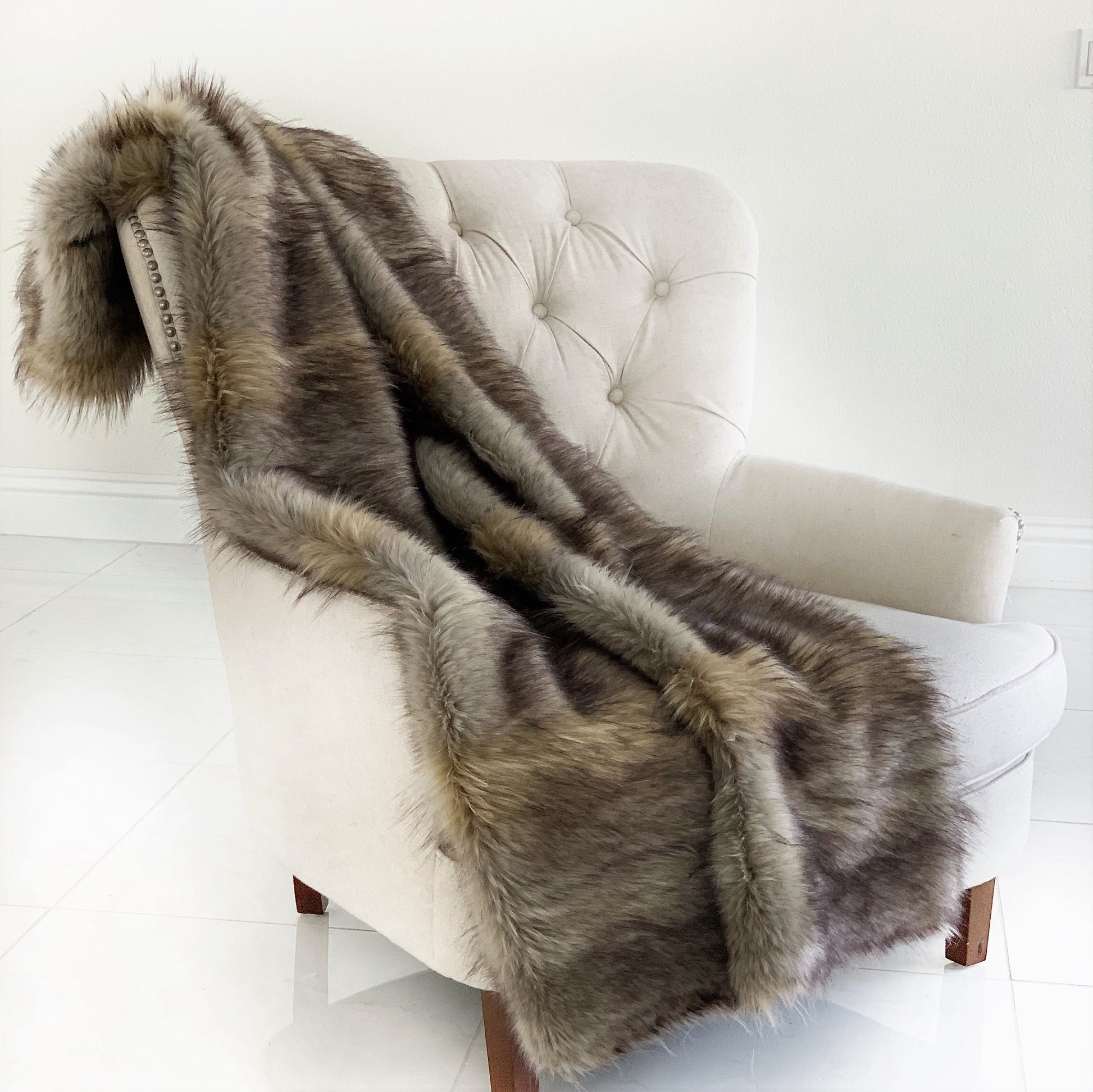 Brown fur throw blanket draped over a white chair in a minimalistic room.