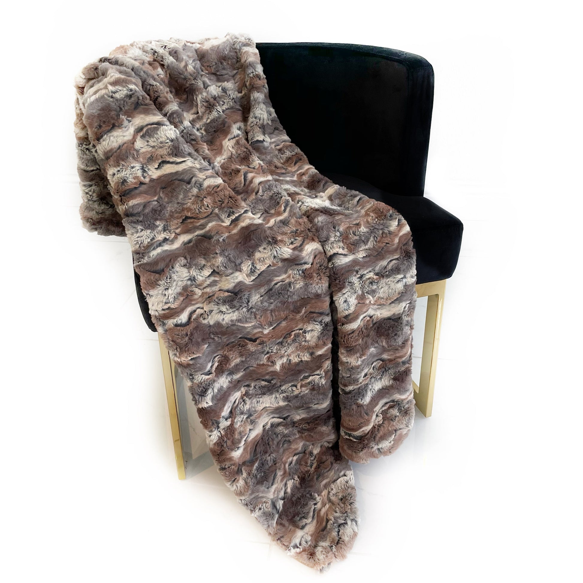 Brown faux fur throw blanket draped over a black chair on a white background