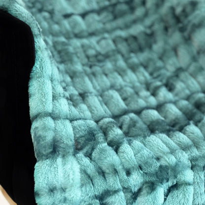 Close-up of a textured teal rug with a wavy pattern.