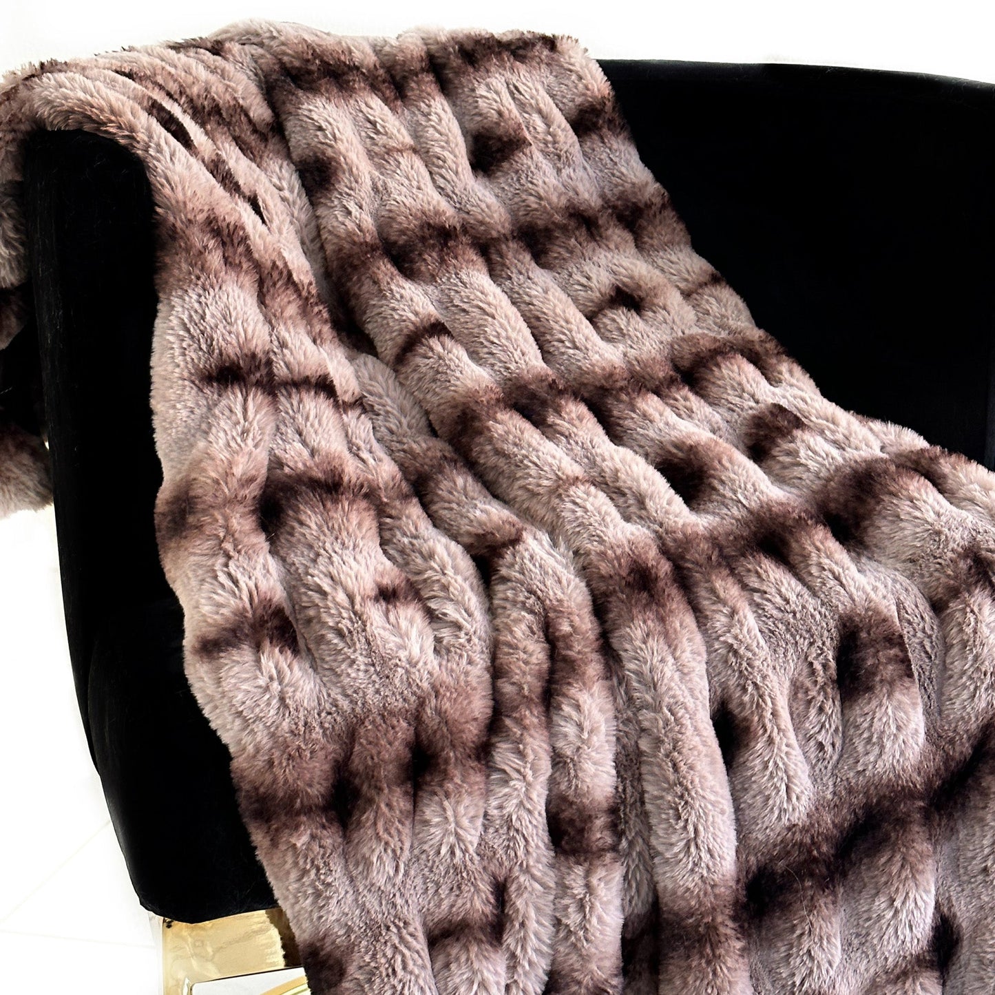 Fluffy brown blanket draped over a black chair on a white background