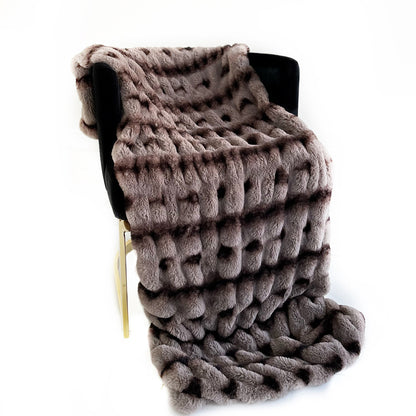 Knitted blanket draped over a chair on a white background