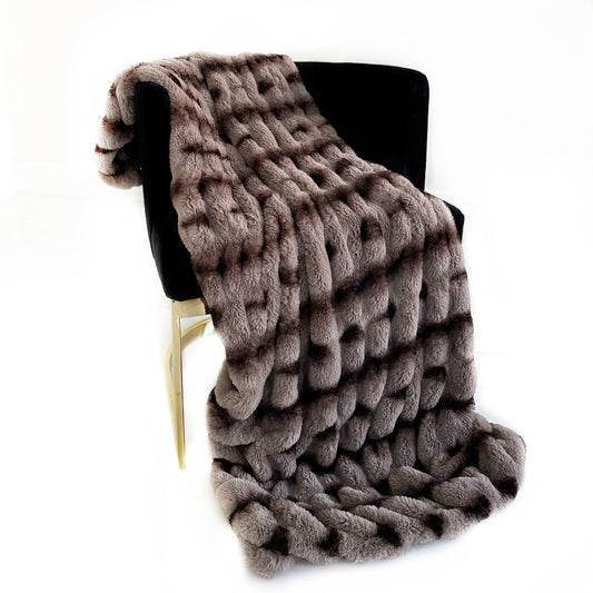 Brown textured blanket draped over a black chair on a white background
