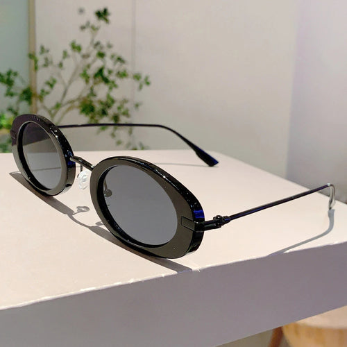Round sunglasses with black frames and dark lenses on a white surface.