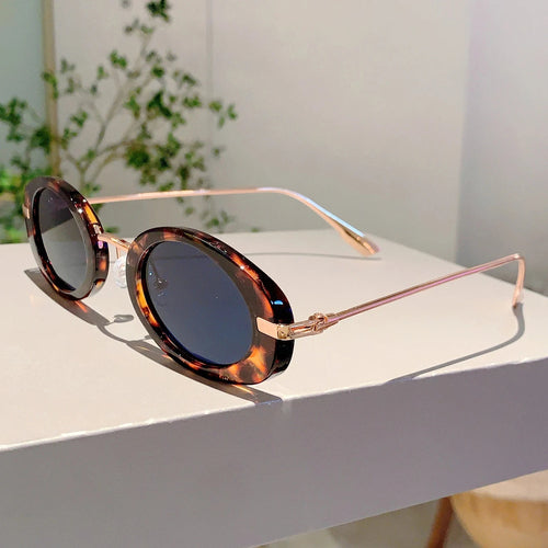 Sunglasses with tortoiseshell frame and dark lenses on a white surface.