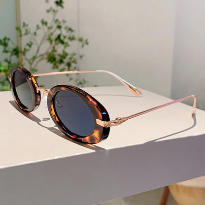 Sunglasses with tortoiseshell frame and dark lenses on a white surface.