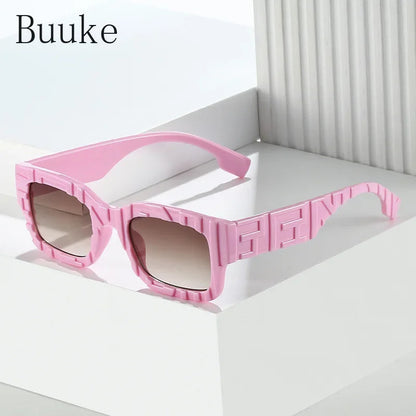 Pink sunglasses with a geometric design on a white background, branded 'Buuke'.