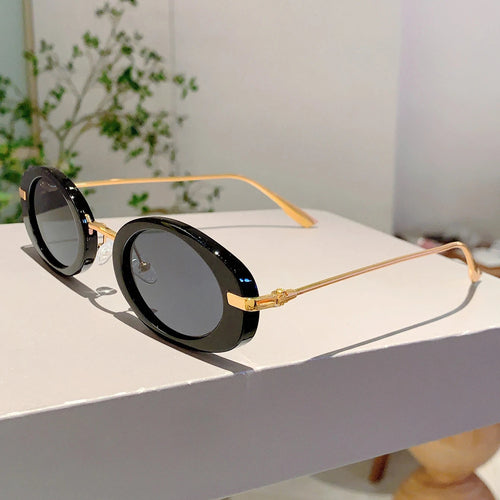 Sunglasses with gold frames and black lenses on a white surface.