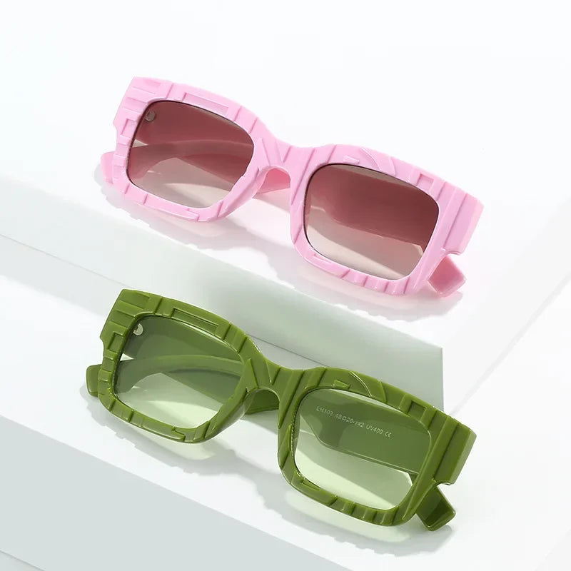 Pink and green sunglasses on a white surface