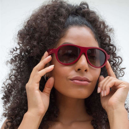 Woman wearing red sunglasses with a neutral background