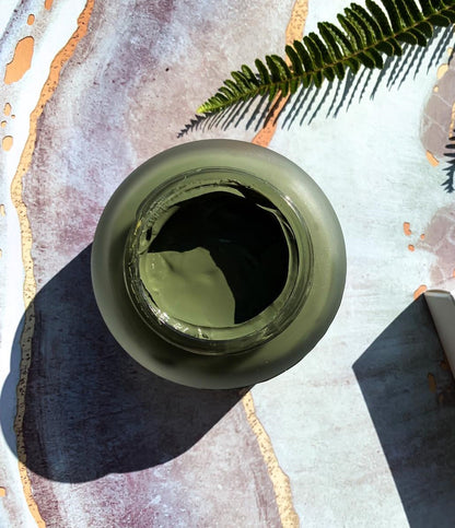 Ceramic jar of green 5G mask on a textured surface with a leaf decoration