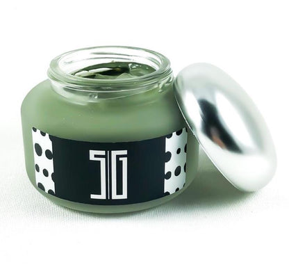 Jar of green cream with a black label and silver lid on a white background