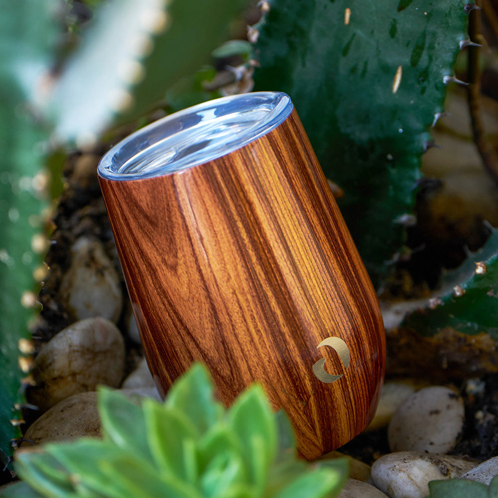 Wooden cup with a brand logo on a natural background with cacti