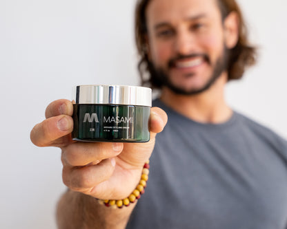 Man holding a jar of Masami hair product against a plain background