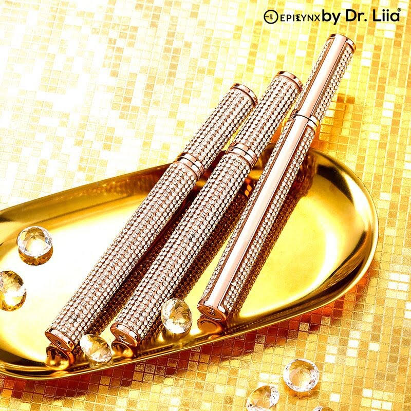 Two rose gold mascaras with gemstone accents on a gold tray with a mosaic background, featuring the Epirynx by Dr. Liia logo.