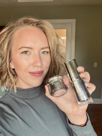 Woman holding two skincare products by Dr. Liia in a home setting