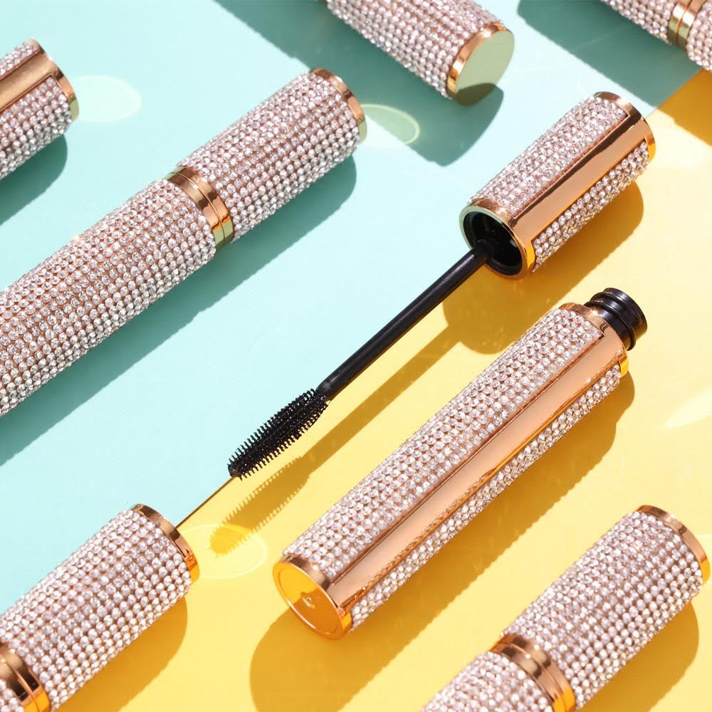 Mascara brushes with rhinestone handles on a colorful background