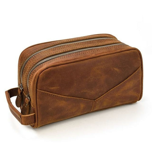 Brown leather toiletry bag with multiple zippers on a white background