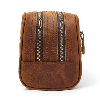 Brown leather toilet bag with two zippers on a white background